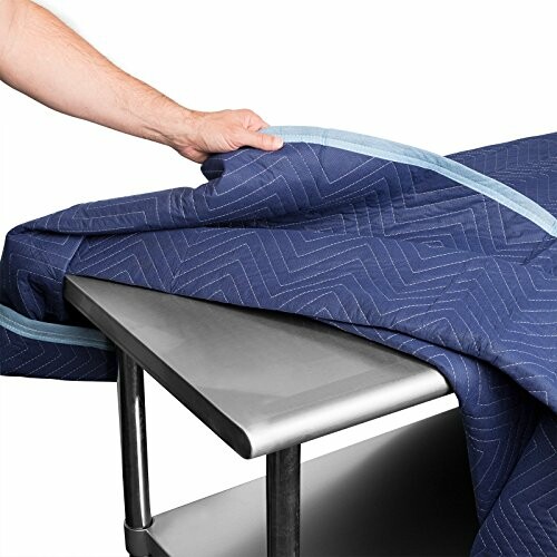 Person draping a blue moving blanket over a metal table.