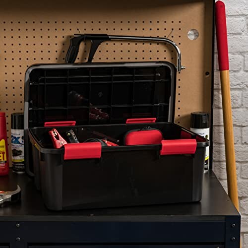 Open toolbox with tools on workbench with pegboard backdrop