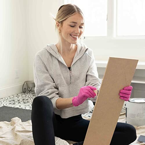 Woman wearing pink gloves working on a DIY project indoors.